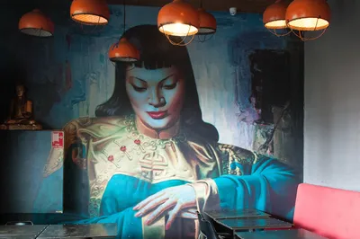 An illustrated mural and copper pendant lights in an Asian Beer Cafe dining room