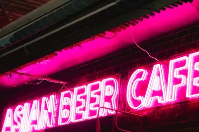 The pink Asian Beer Cafe neon sign glowing at night