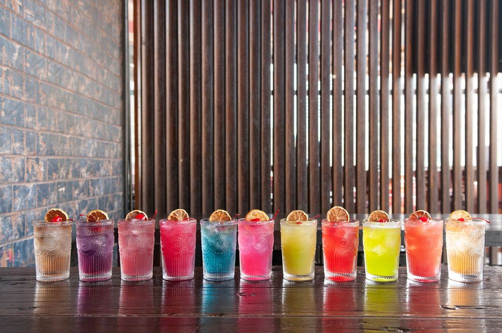 A row of colourful cocktails in individual glasses on the bar at Asian Beer Cafe