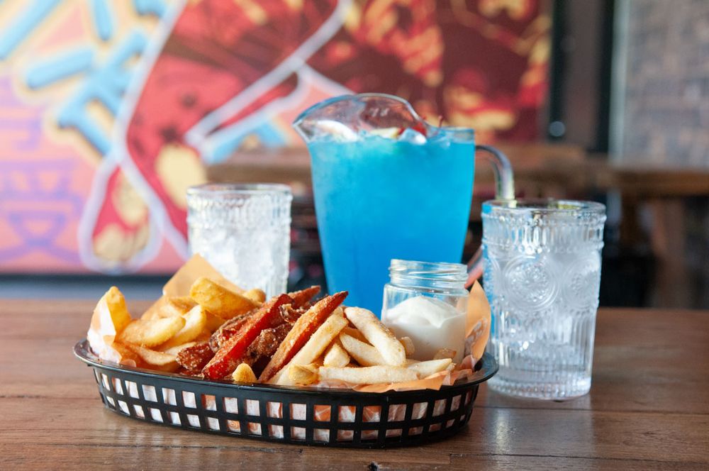 A basket of fries with a blue cocktail and iced water at Asian Beer Cafe