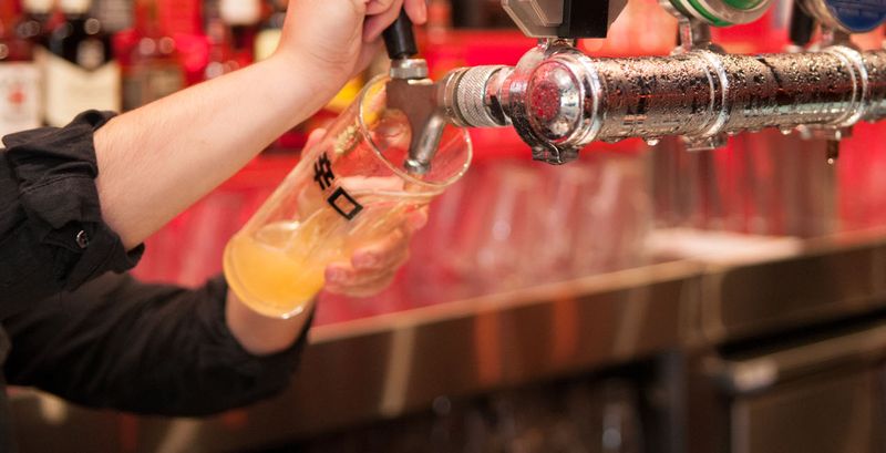 A hand pulling a beer at the Asian Beer Cafe bar